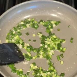 Add chopped green onions and minced garlic